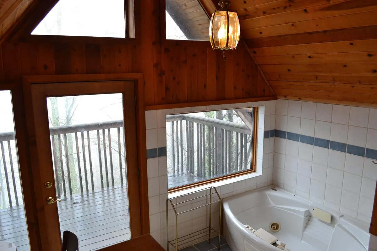 This bathroom scene highlights a soaking bathtub set beside a large window, wooden beams, and a stylish light fixture. The space feels serene, private, and luxurious—ideal for unwinding after a day of exploration.
